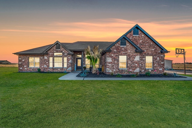 view of front of property featuring brick siding, a shingled roof, and a front yard