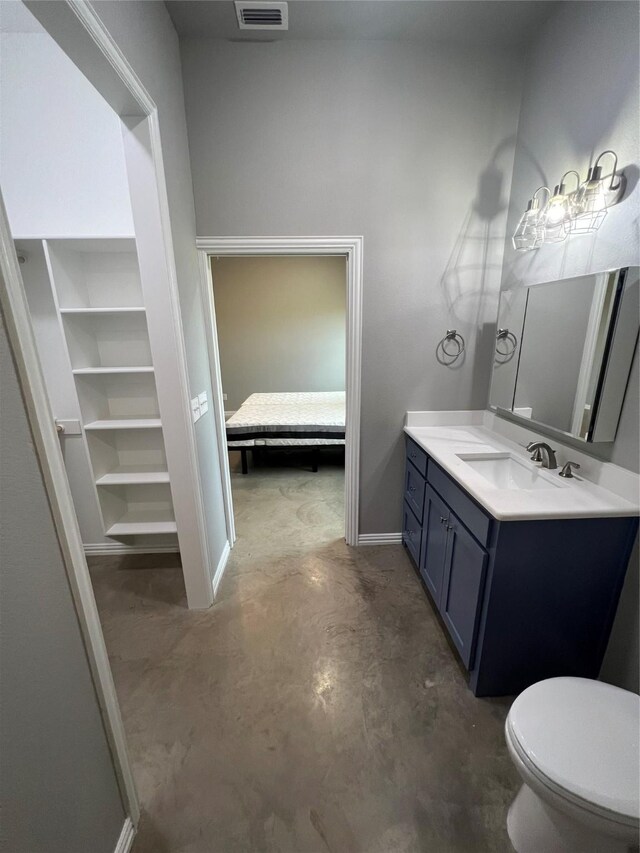 bathroom with vanity, toilet, and concrete flooring