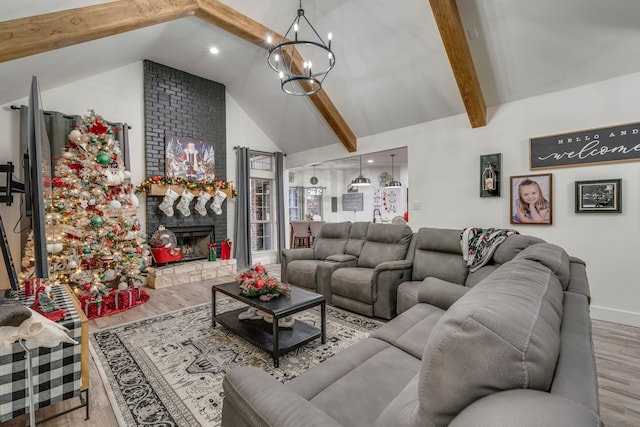 living room featuring an inviting chandelier, a stone fireplace, high vaulted ceiling, beamed ceiling, and light wood-type flooring