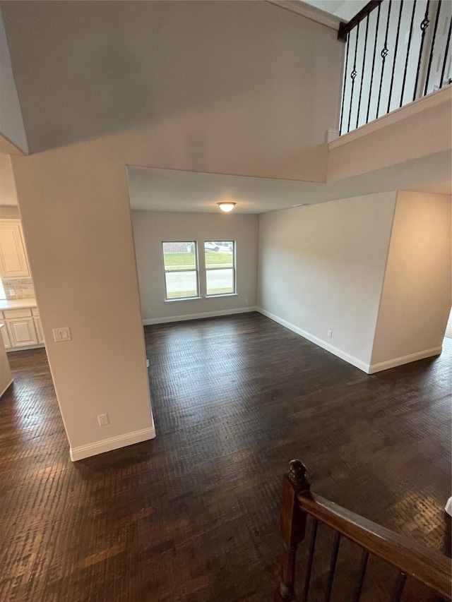 unfurnished living room with a towering ceiling and dark wood-type flooring