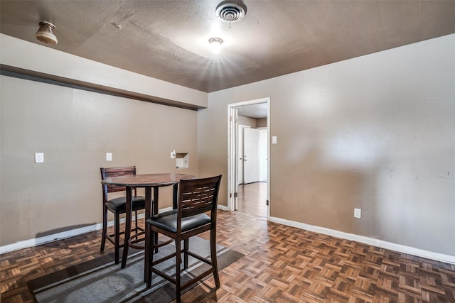 dining room featuring a textured ceiling and dark parquet floors