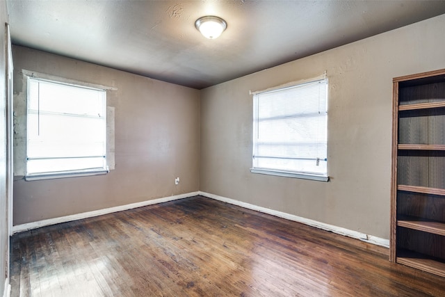 spare room featuring plenty of natural light and dark hardwood / wood-style floors