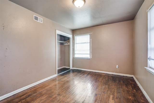 unfurnished bedroom with a closet and dark wood-type flooring