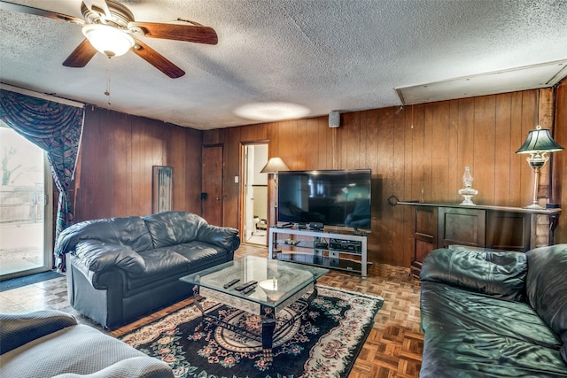 living room featuring parquet floors, a textured ceiling, and wooden walls