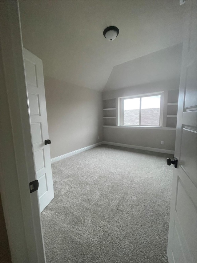 additional living space featuring vaulted ceiling, carpet, and built in shelves