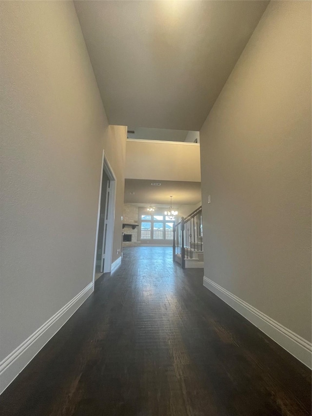 corridor featuring dark wood-type flooring and a chandelier