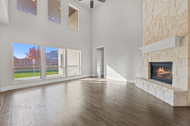 unfurnished living room with hardwood / wood-style flooring, a stone fireplace, and ceiling fan