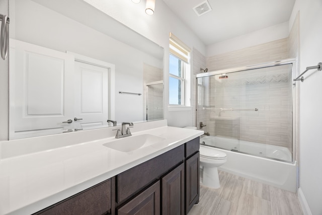 full bathroom with vanity, enclosed tub / shower combo, and toilet