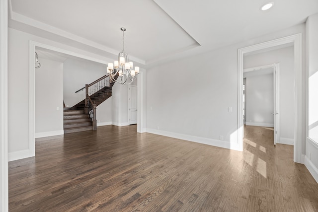 unfurnished room featuring dark wood-type flooring, a raised ceiling, and an inviting chandelier