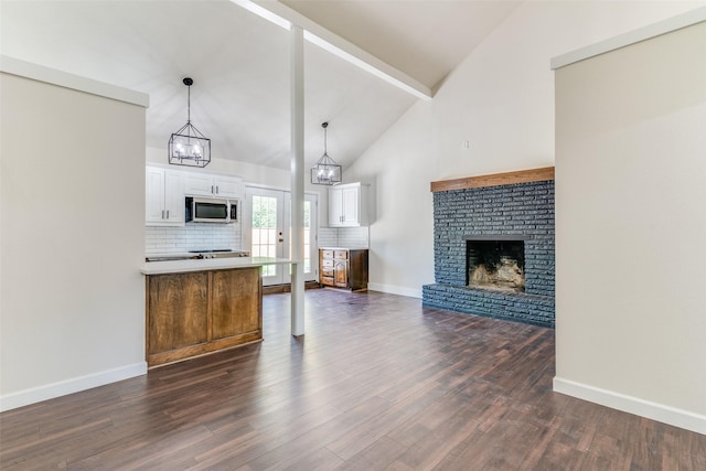 kitchen with white cabinetry, a brick fireplace, dark hardwood / wood-style floors, backsplash, and decorative light fixtures