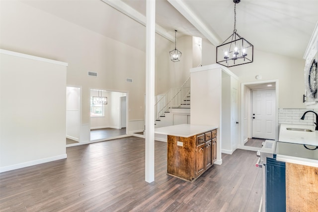 kitchen with high vaulted ceiling, sink, hanging light fixtures, tasteful backsplash, and dark hardwood / wood-style flooring