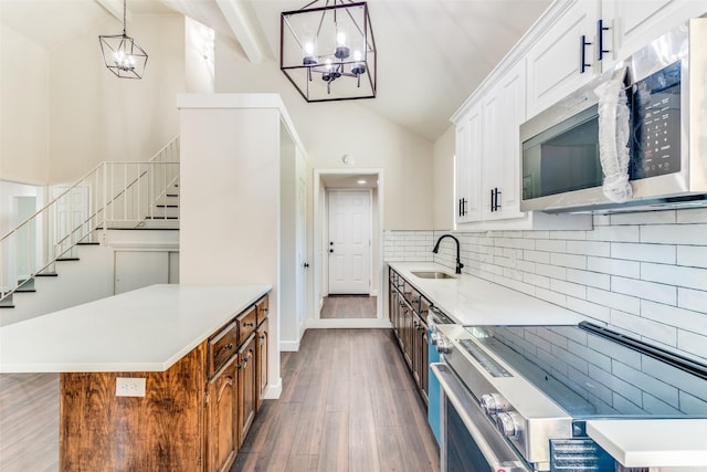 kitchen with decorative light fixtures, stainless steel appliances, white cabinetry, and sink