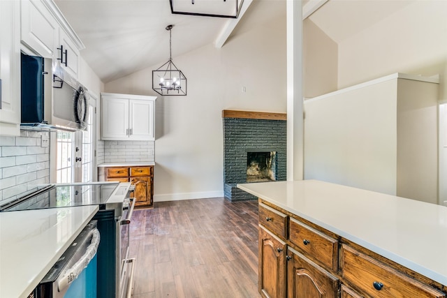 kitchen with appliances with stainless steel finishes, tasteful backsplash, dark wood-type flooring, pendant lighting, and white cabinetry