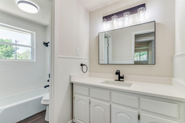 full bathroom featuring hardwood / wood-style flooring, vanity, tiled shower / bath combo, and toilet