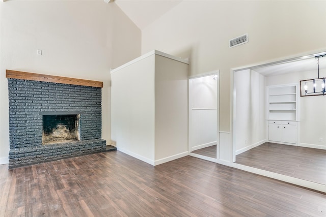 unfurnished living room featuring dark hardwood / wood-style floors, a fireplace, high vaulted ceiling, and built in shelves