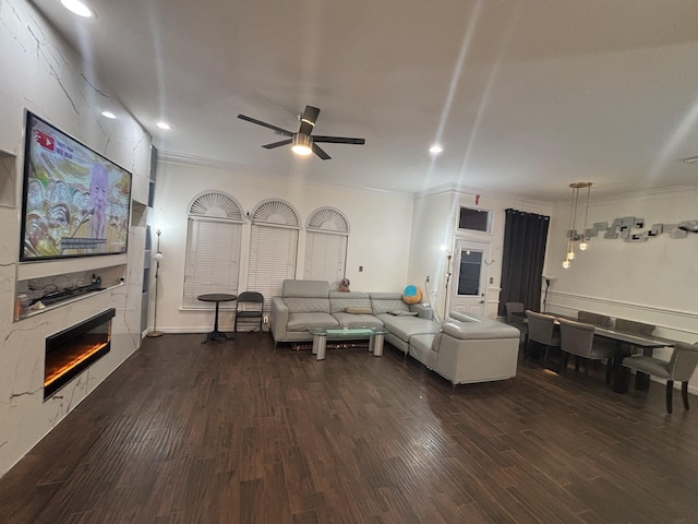 living room with dark hardwood / wood-style flooring, crown molding, and ceiling fan