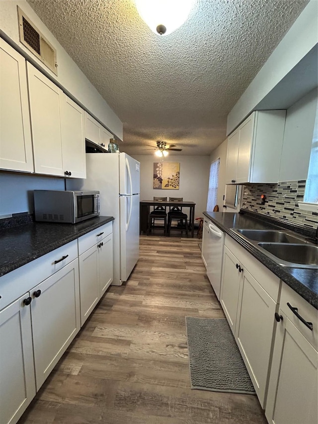 kitchen with sink, light wood-type flooring, white cabinets, decorative backsplash, and white appliances