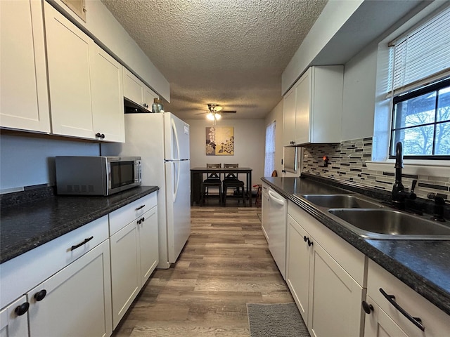 kitchen with white cabinetry, white appliances, sink, and hardwood / wood-style flooring