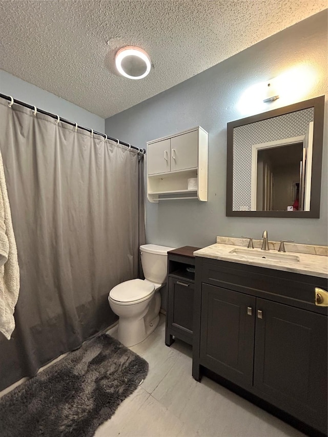 bathroom with vanity, toilet, and a textured ceiling