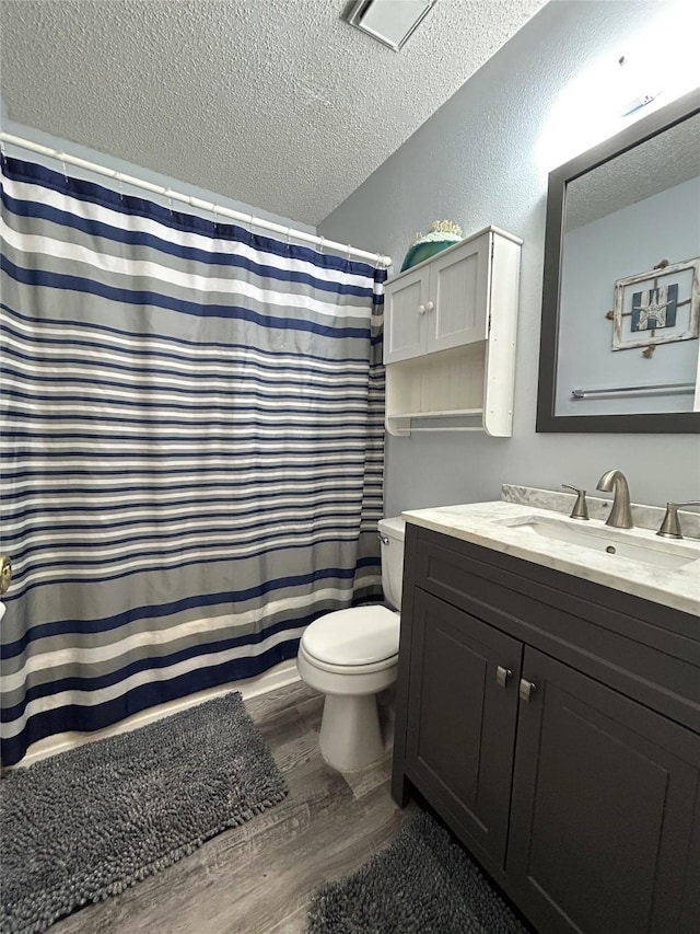 bathroom featuring wood-type flooring, vanity, a textured ceiling, and toilet