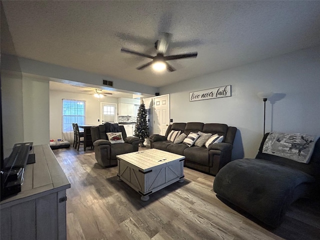 living room with hardwood / wood-style floors, a textured ceiling, and ceiling fan