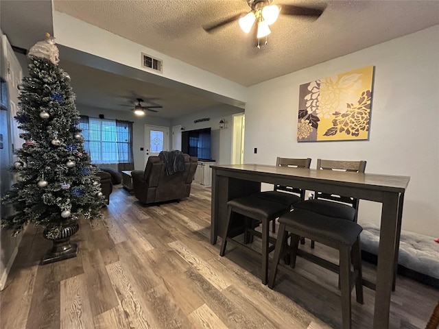 dining room with ceiling fan, hardwood / wood-style flooring, and a textured ceiling