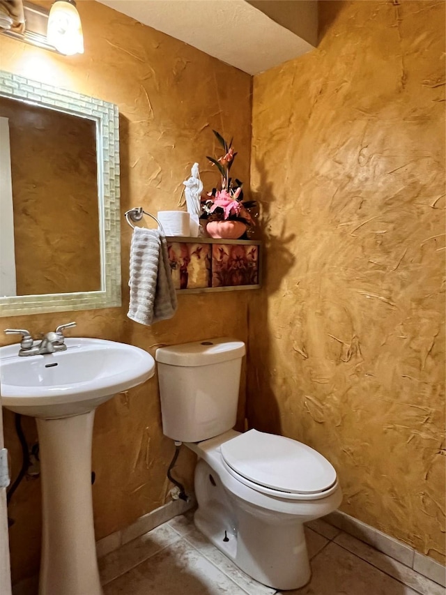 bathroom with sink, toilet, and tile patterned flooring