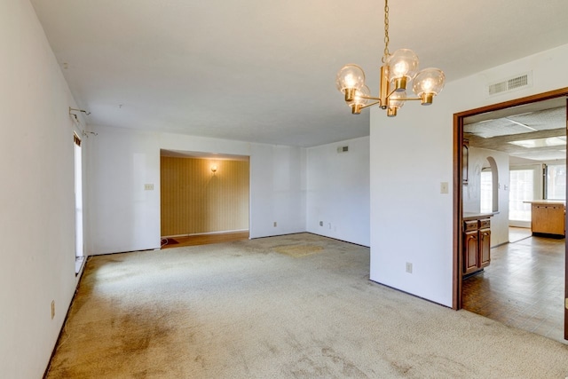 carpeted empty room featuring a notable chandelier