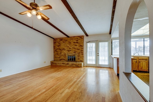 unfurnished living room featuring french doors, light wood-type flooring, ceiling fan, sink, and beam ceiling