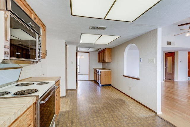 kitchen with a textured ceiling, electric range, ceiling fan with notable chandelier, and light wood-type flooring