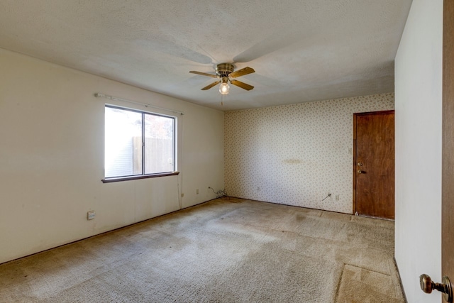 carpeted spare room with ceiling fan and a textured ceiling