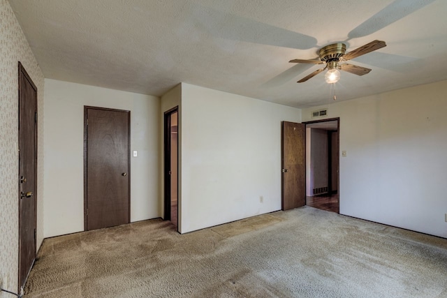 spare room featuring a textured ceiling, light colored carpet, and ceiling fan