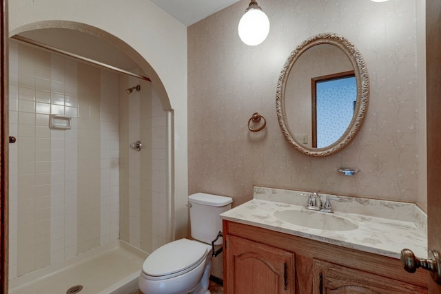 bathroom with a tile shower, vanity, and toilet