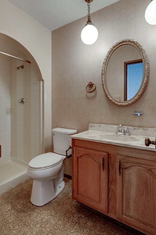 bathroom featuring toilet, vanity, and tiled shower