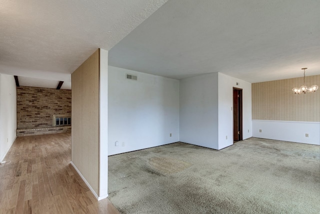 unfurnished room featuring hardwood / wood-style floors, a textured ceiling, and a notable chandelier