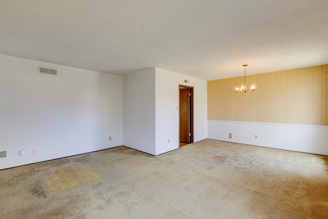 carpeted spare room with a notable chandelier