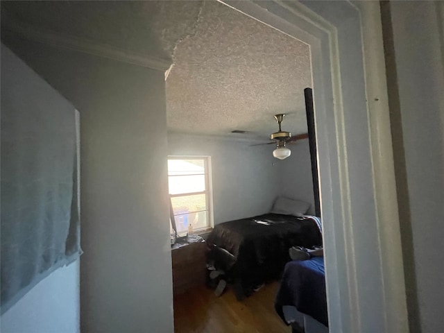 bedroom with wood-type flooring, a textured ceiling, ceiling fan, and crown molding