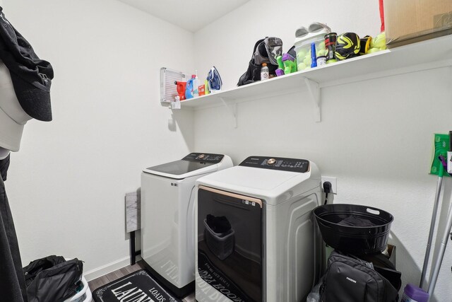 washroom with washing machine and dryer and hardwood / wood-style flooring