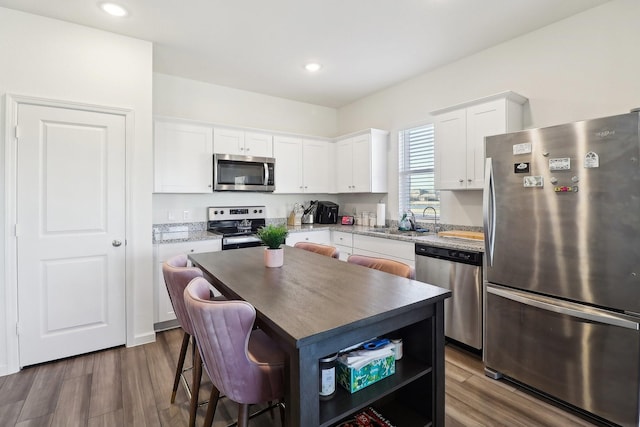 kitchen featuring a kitchen island, stainless steel appliances, white cabinetry, and dark wood-type flooring