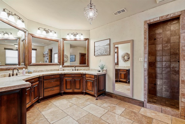 12201 Madison Ln, Justin, TX 76247 - bathroom featuring stone tile floors, double vanity, tiled shower, and a chandelier
