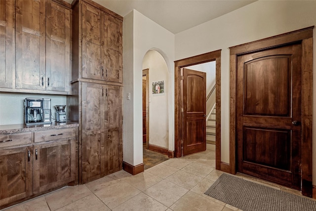 12201 Madison Ln, Justin, TX 76247 - hallway featuring arched walkways, light tile patterned floors, baseboards, and stairs