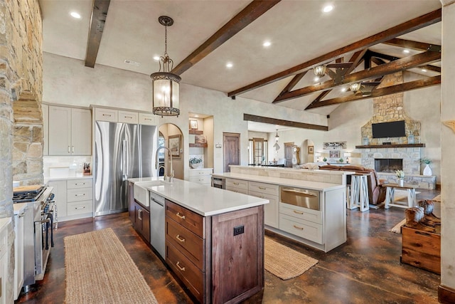 kitchen featuring appliances with stainless steel finishes, high vaulted ceiling, decorative light fixtures, a center island with sink, and beam ceiling