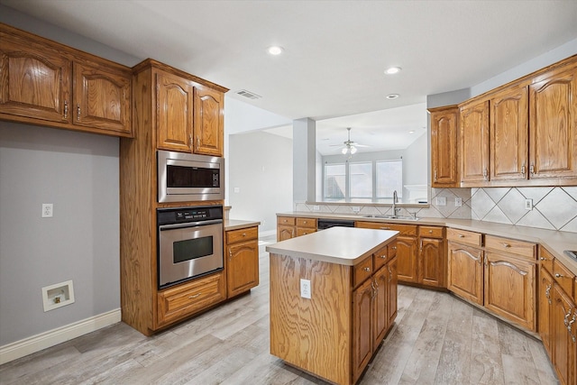 kitchen with appliances with stainless steel finishes, sink, decorative backsplash, a center island, and light hardwood / wood-style floors