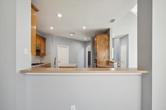 kitchen featuring sink, decorative backsplash, gas stovetop, and kitchen peninsula