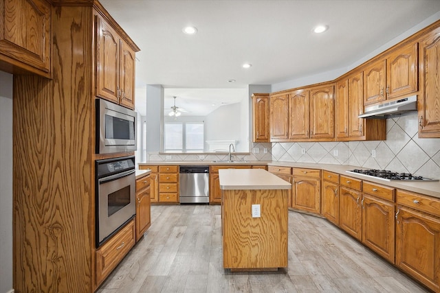 kitchen featuring sink, light hardwood / wood-style flooring, stainless steel appliances, a center island, and tasteful backsplash