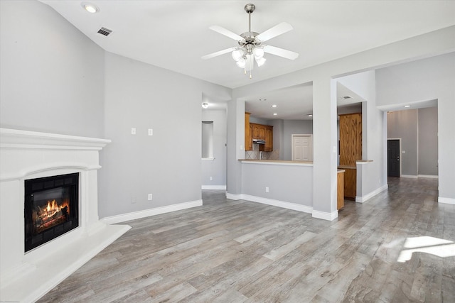 unfurnished living room with ceiling fan and light wood-type flooring