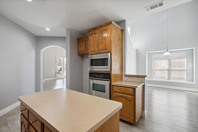 kitchen with appliances with stainless steel finishes, pendant lighting, a center island, light hardwood / wood-style floors, and plenty of natural light