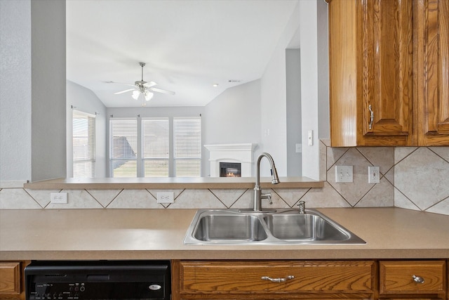 kitchen featuring vaulted ceiling, tasteful backsplash, sink, dishwashing machine, and ceiling fan