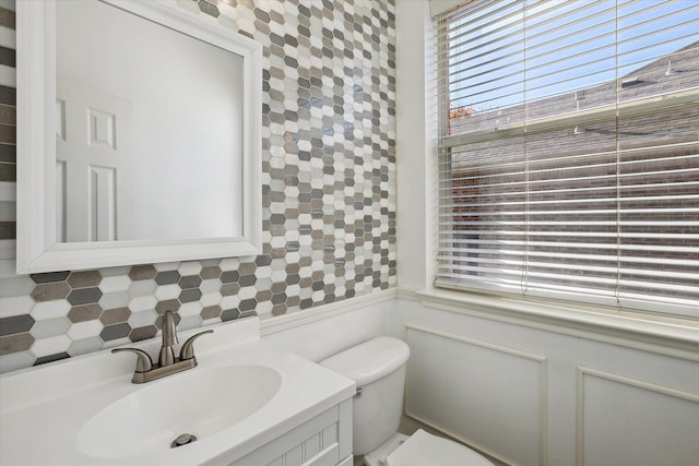 bathroom featuring vanity, backsplash, and toilet