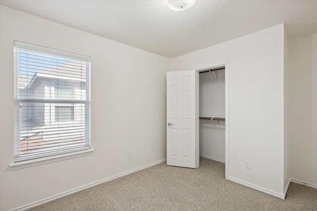 unfurnished bedroom with light colored carpet and a closet